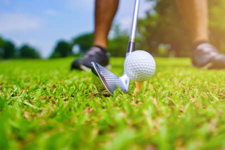 Golf ball on green grass ready to be struck on golf course.