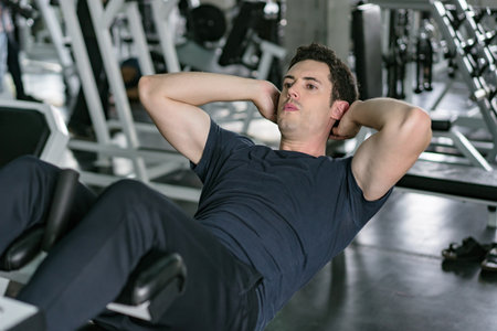 Handsome man exercising doing sit up abdominal exercise in gym.の写真素材