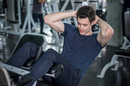 Handsome man exercising doing sit up abdominal exercise in gym.の写真素材