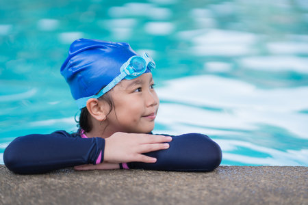 little girl smiling wearing swimming glasses in swimming pool. children playing in swimming pool on summerの写真素材