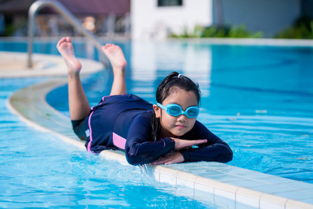 little girl smiling wearing swimming glasses in swimming pool. children playing in swimming pool on summerの写真素材
