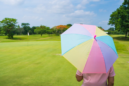 women Golfers under umbrella on green grass at golf course.の写真素材