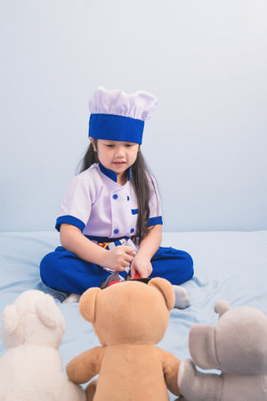 Happy girls in clothes and chef cap playing with a doll to be a chef. child dreams of becoming a chef.の写真素材