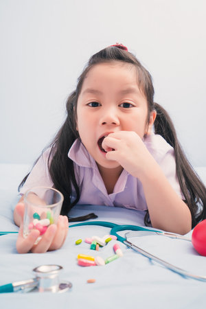 Happy cute girls in white medical uniform and stethoscope act like doctor. child dreams of becoming a doctor career concept.の写真素材