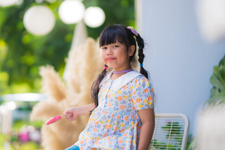 Cute smiling little girl eating an ice cream on a stick.の写真素材