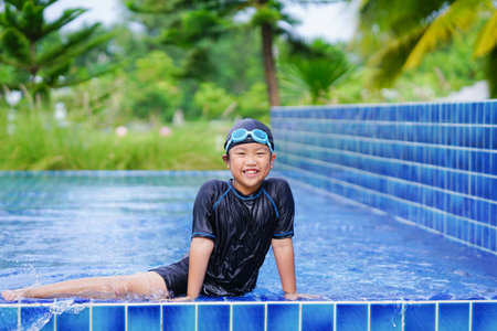 Happy asian boy in swimming suit and goggles playing in swimming poolの写真素材