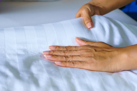 Female Hand set up white bed sheet in bedroom or maid hands making bed in a hotel room.の写真素材