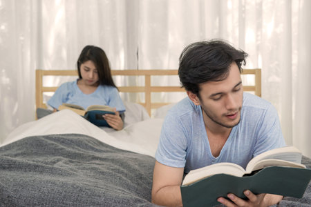 young loving couple reading a book on bedroom at home.の写真素材