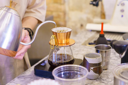 barista preparing coffee with drip coffee and drop the water on coffee ground with filter.