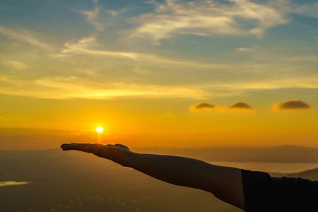 Woman Hand holding sunset above the mountain beautiful landscapeの写真素材