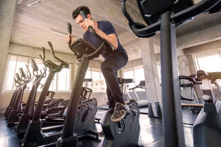 sport man working out on exercise bike at sport health club.の写真素材