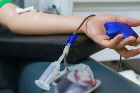 woman as blood donor at donation with a bouncy ball holding in hand.の写真素材