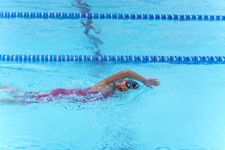 Swimmer child swims freestyle swimming style in a race swimming pool. Water sports and competition, learning to swim classes for children.の写真素材