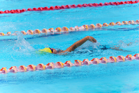 Swimmer child swims backstroke swimming style in a race swimming pool. Water sports and competition, learning to swim classes for children.の写真素材