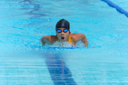 Swimmer child swims butterfly swimming style in a race swimming pool. Water sports and competition, learning to swim classes for children.の写真素材