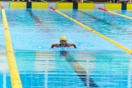 Swimmer child swims butterfly swimming style in a race swimming pool. Water sports and competition, learning to swim classes for children.の写真素材