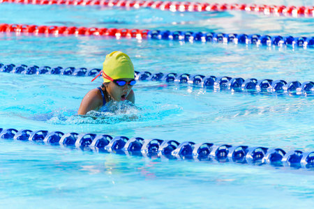 Swimmer child swims breaststroke swimming style in a race swimming pool. Water sports and competition, learning to swim classes for children.の写真素材