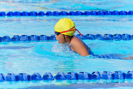 Swimmer child swims breaststroke swimming style in a race swimming pool. Water sports and competition, learning to swim classes for childrenの写真素材