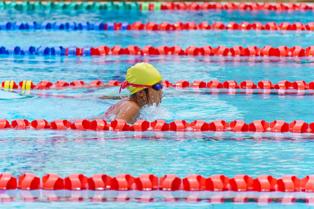 Swimmer child swims breaststroke swimming style in a race swimming pool. Water sports and competition, learning to swim classes for childrenの写真素材