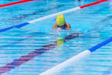 Swimmer child swims breaststroke swimming style in a race swimming pool. Water sports and competition, learning to swim classes for childrenの写真素材