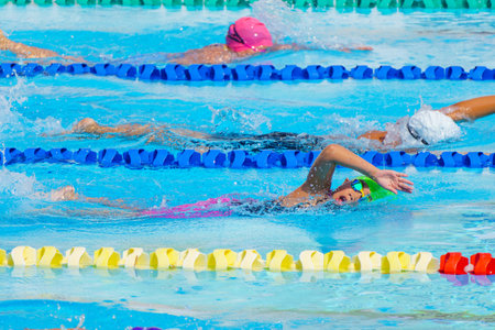 Swimmer child swims freestyle swimming style in a race swimming pool. Water sports and competition, learning to swim classes for children.の写真素材
