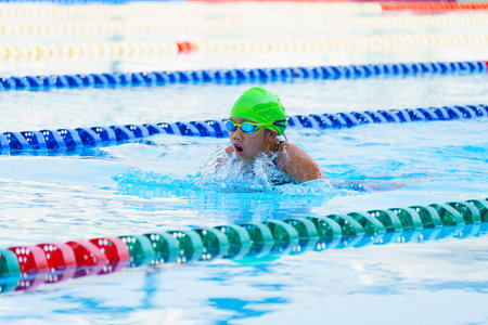 Swimmer child swims breaststroke swimming style in a race swimming pool. Water sports and competition, learning to swim classes for childrenの写真素材