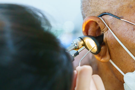 Patient is seen by an otolaryngologist. ENT doctor examines a patient. An otolaryngologist examines a patient's inner ear using an otoscope. Treatment of inflammation disease of earsの写真素材