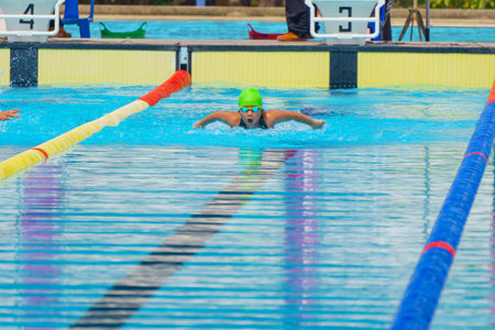 Swimmer child swims butterfly swimming style in a race swimming pool. Water sports and competition, learning to swim classes for children.の写真素材