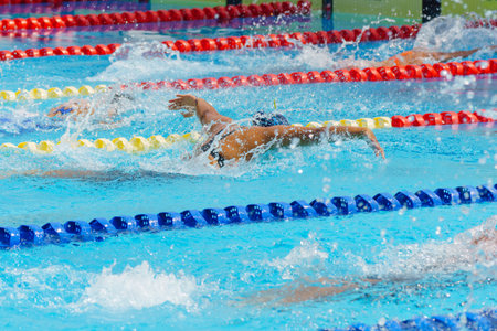 Swimmer child swims butterfly swimming style in a race swimming pool. Water sports and competition, learning to swim classes for children.の写真素材