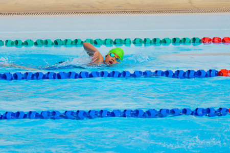 Swimmer child swims freestyle swimming style in a race swimming pool. Water sports and competition, learning to swim classes for children.の写真素材