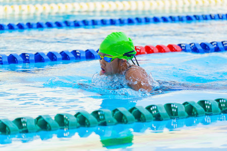 Swimmer child swims breaststroke swimming style in a race swimming pool. Water sports and competition, learning to swim classes for childrenの写真素材