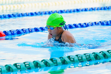 Swimmer child swims breaststroke swimming style in a race swimming pool. Water sports and competition, learning to swim classes for childrenの写真素材