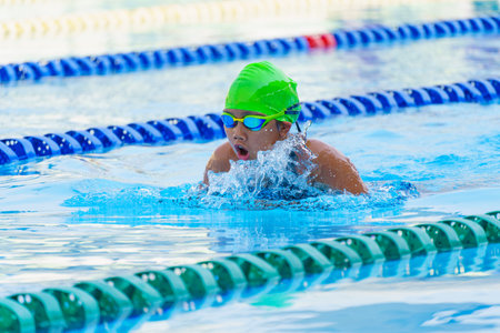 Swimmer child swims breaststroke swimming style in a race swimming pool. Water sports and competition, learning to swim classes for childrenの写真素材