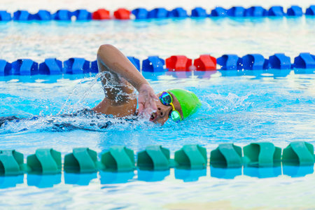 Swimmer child swims freestyle swimming style in a race swimming pool. Water sports and competition,...