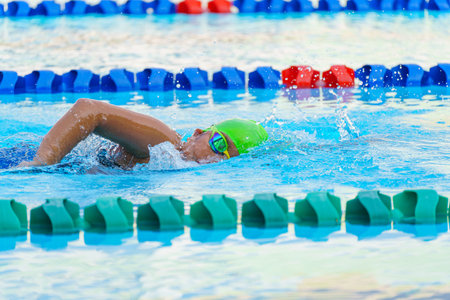 Swimmer child swims freestyle swimming style in a race swimming pool. Water sports and competition, learning to swim classes for children.の写真素材