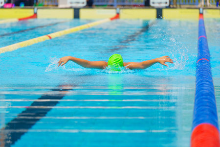 Swimmer child swims butterfly swimming style in a race swimming pool. Water sports and competition, learning to swim classes for children.の写真素材