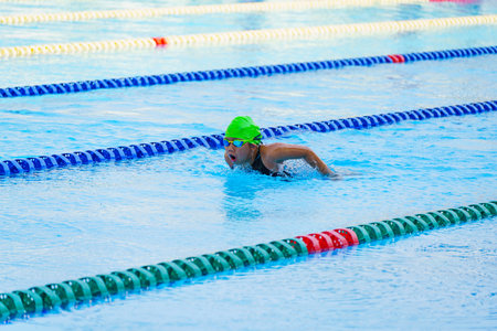 Swimmer child swims butterfly swimming style in a race swimming pool. Water sports and competition, learning to swim classes for children.の写真素材