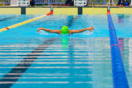 Swimmer child swims butterfly swimming style in a race swimming pool. Water sports and competition, learning to swim classes for children.の写真素材