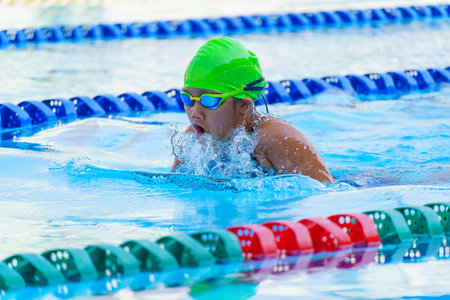 Swimmer child swims breaststroke swimming style in a race swimming pool. Water sports and competition, learning to swim classes for childrenの写真素材
