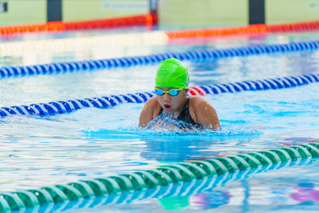 Swimmer child swims breaststroke swimming style in a race swimming pool. Water sports and competition, learning to swim classes for childrenの写真素材