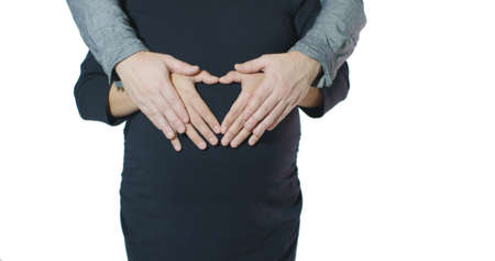 Loving Couple Embrace Arms Around Pregnant Belly Hands Forming Heart Shape - Valentines Day Conceptの写真素材