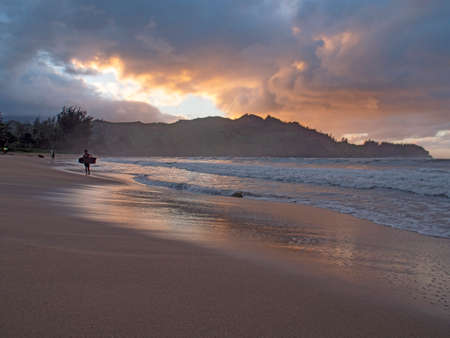 Hanalei Beach, Kauai, Hawaii/USA - November 2018: Kid surfer holding bodyboard leaving ocean at sunsetのeditorial素材