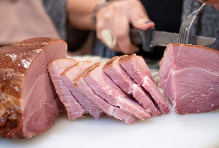 Carving Ham Slices on Cutting Board With Knife and Forkの写真素材