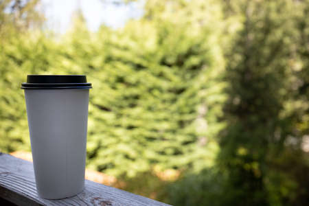 Coffee Cup on Outdoor Deck in Forest Tree Nature Backgroundの写真素材