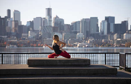 Female Yoga Instructor Doing One Legged King Pigeon Yoga Pose in City Downtown Waterfrontの写真素材