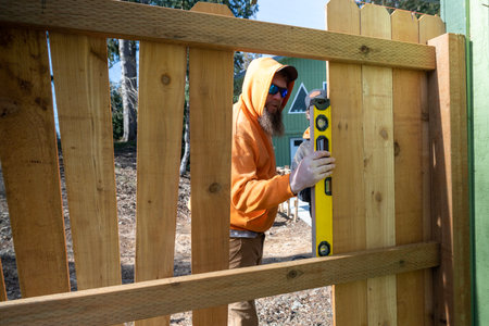 Using a Level Tool to Measure Wood Pickets on Fence For Leveling on Work in Progressの写真素材