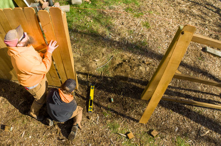Two Construction Workers Attaching Screw in Picket Boards to Fence With Precisionの写真素材