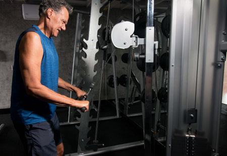 Senior Man working out doing Triceps Extensions in the gym