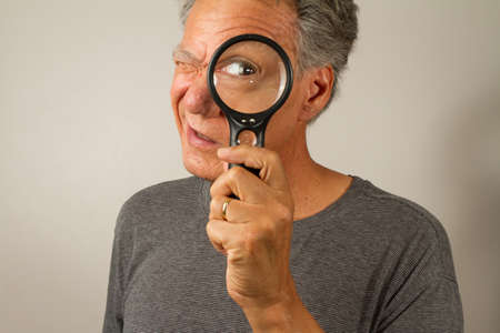 Senior Man looking through a Magnifying Glassの写真素材