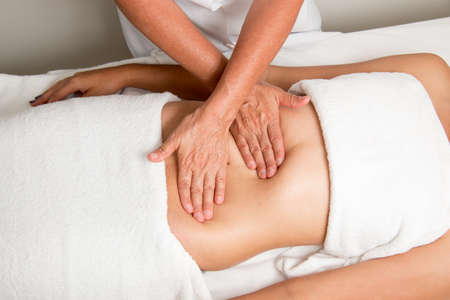 Massage Therapist Massaging a young women stomachの写真素材